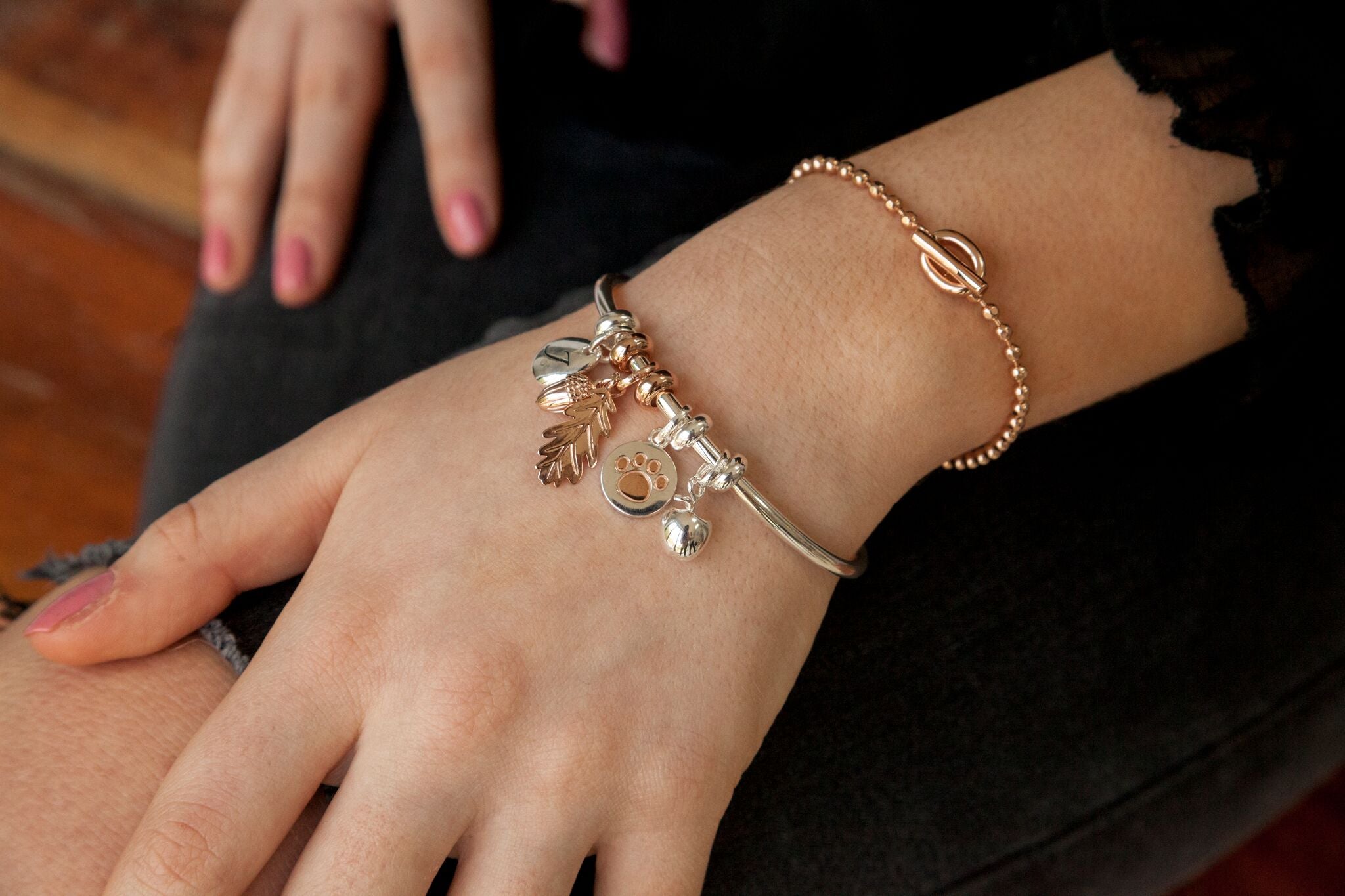 Close-up of a hand wearing a bracelet with charms on a dark background