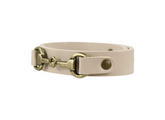 Beige leather strap with brass hardware on a white background