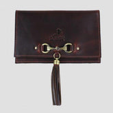 A brown leather clutch bag with a metallic snaffle fitment and a magnetic clasp closure. It features tassel detailing and appears to be of medium size.
