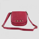 A pink leather handbag with a snaffle bit fitment and a magnetic button closure, featuring a shoulder strap.