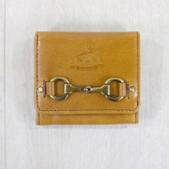 A compact tan leather purse with a metallic bit decoration in the center, closed with a snap button.