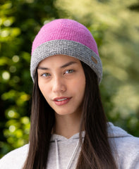 A woman wearing a pink and gray knit turn up cap.