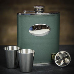 A green leather hip flask set with stainless steel cups and a pouring funnel, displayed on a dark background.