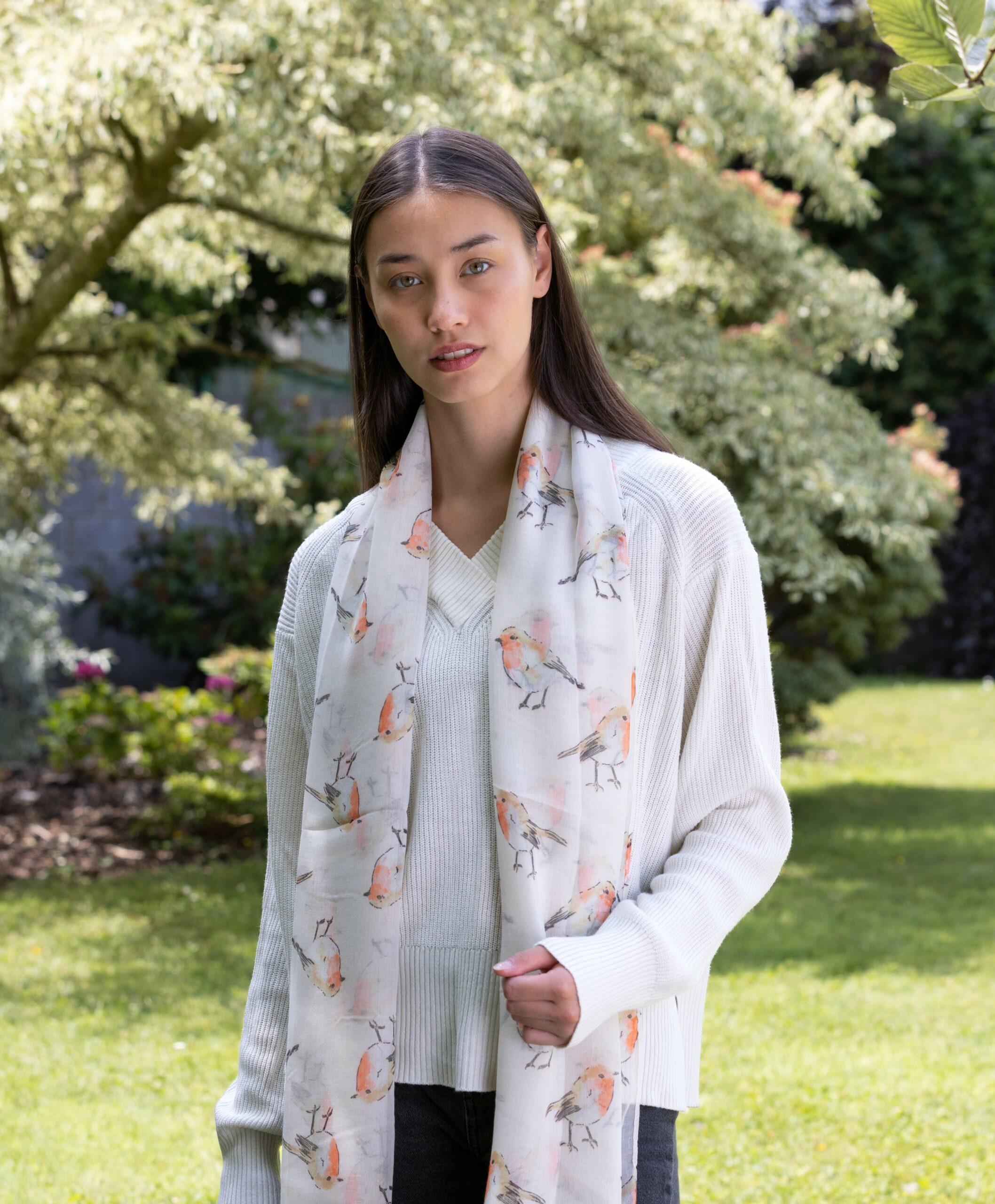A woman wearing a cream-colored polyester scarf with a robin print.