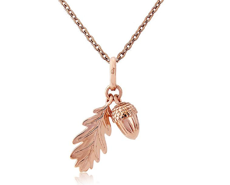 A rose gold pendant featuring an acorn and leaf charm, attached to a rose gold chain.