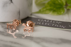 Rose gold horse-shaped earrings on a marble surface with 'Gallop Collection' card.