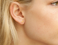 Close-up of a person wearing a gold earring with a small design.