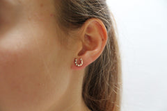 Close-up of an ear wearing a small hoop earring with a plain background