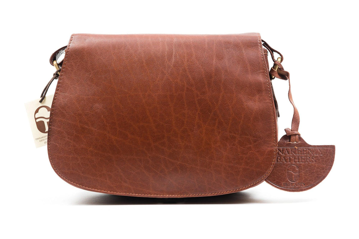 A classic tan saddle bag with rounded edges, an adjustable shoulder strap, and a zippered central pocket, hand made in Ireland.
