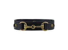 Black leather bracelet with brass horse bit design on a white background