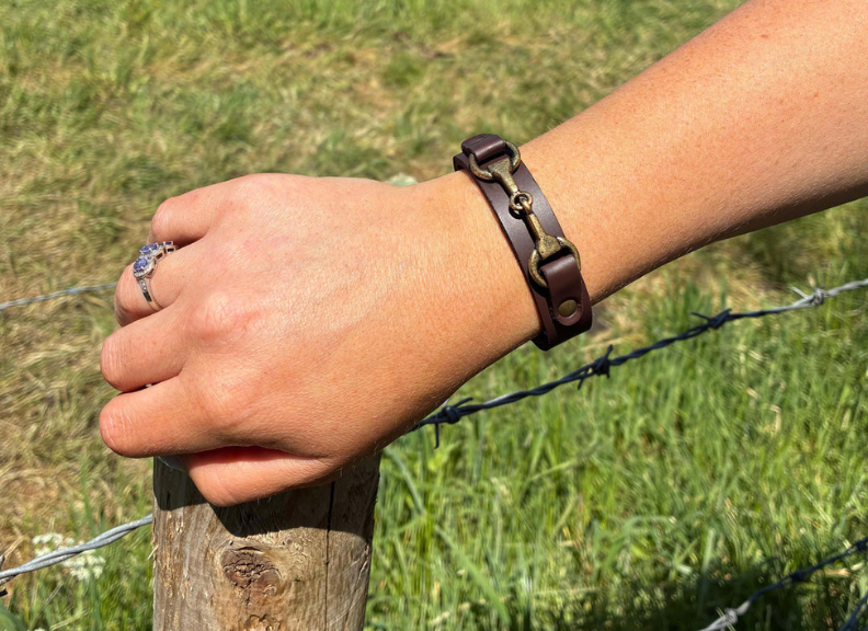 Hand wearing a leather bracelet on a grassy background