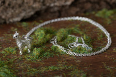 Silver necklace with a horse pendant on a wooden surface with green moss