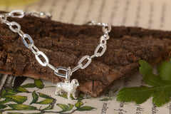 Silver bracelet with a dog charm on a textured surface