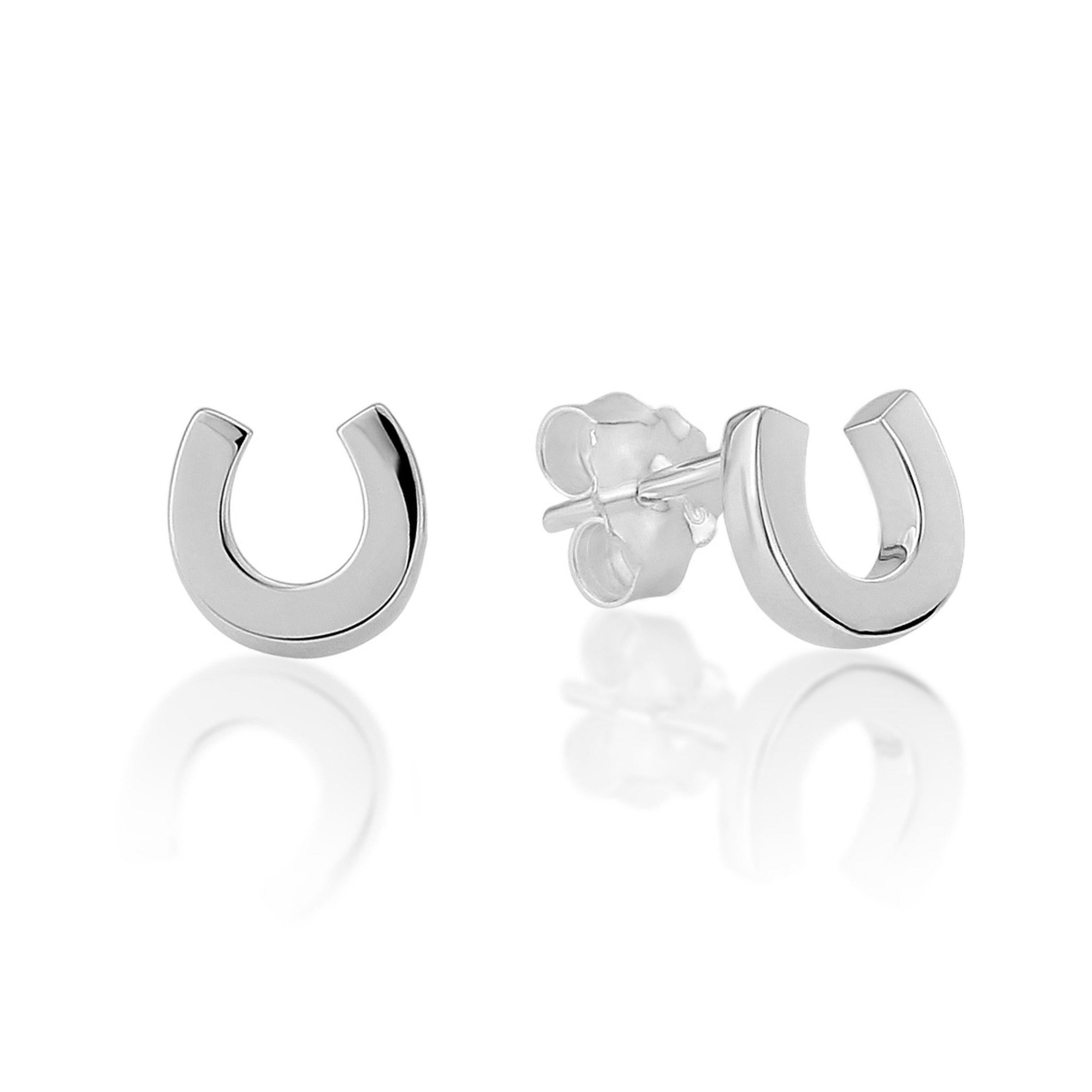 A pair of horseshoe-shaped sterling silver stud earrings with a glossy finish, displayed with a reflection on a smooth surface.