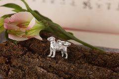 Silver dog-shaped ring on a wooden surface with a pink flower in the background