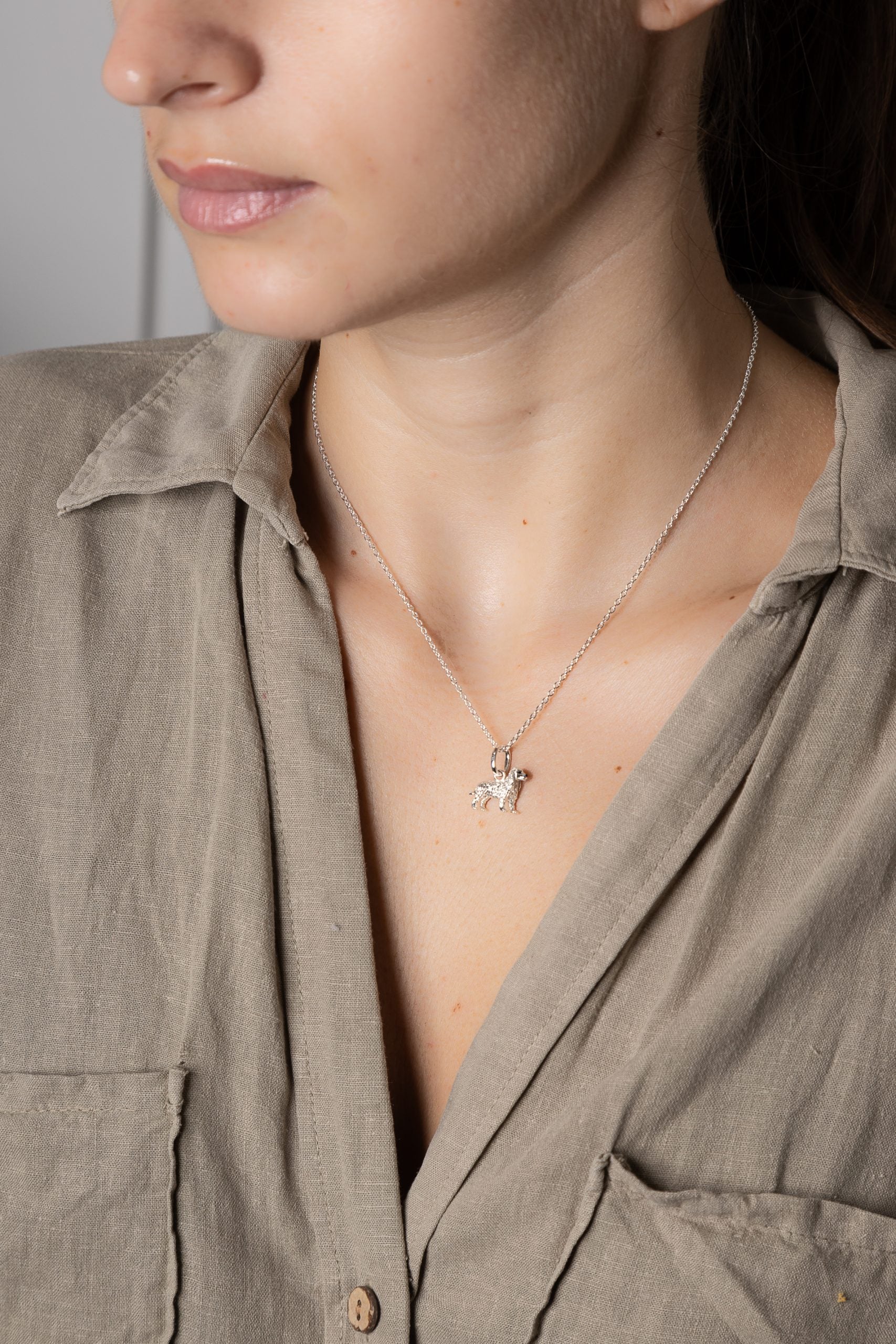 Close-up of a person wearing a necklace with a star pendant, set against a neutral background.