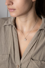 Close-up of a person wearing a necklace with a star pendant, set against a neutral background.
