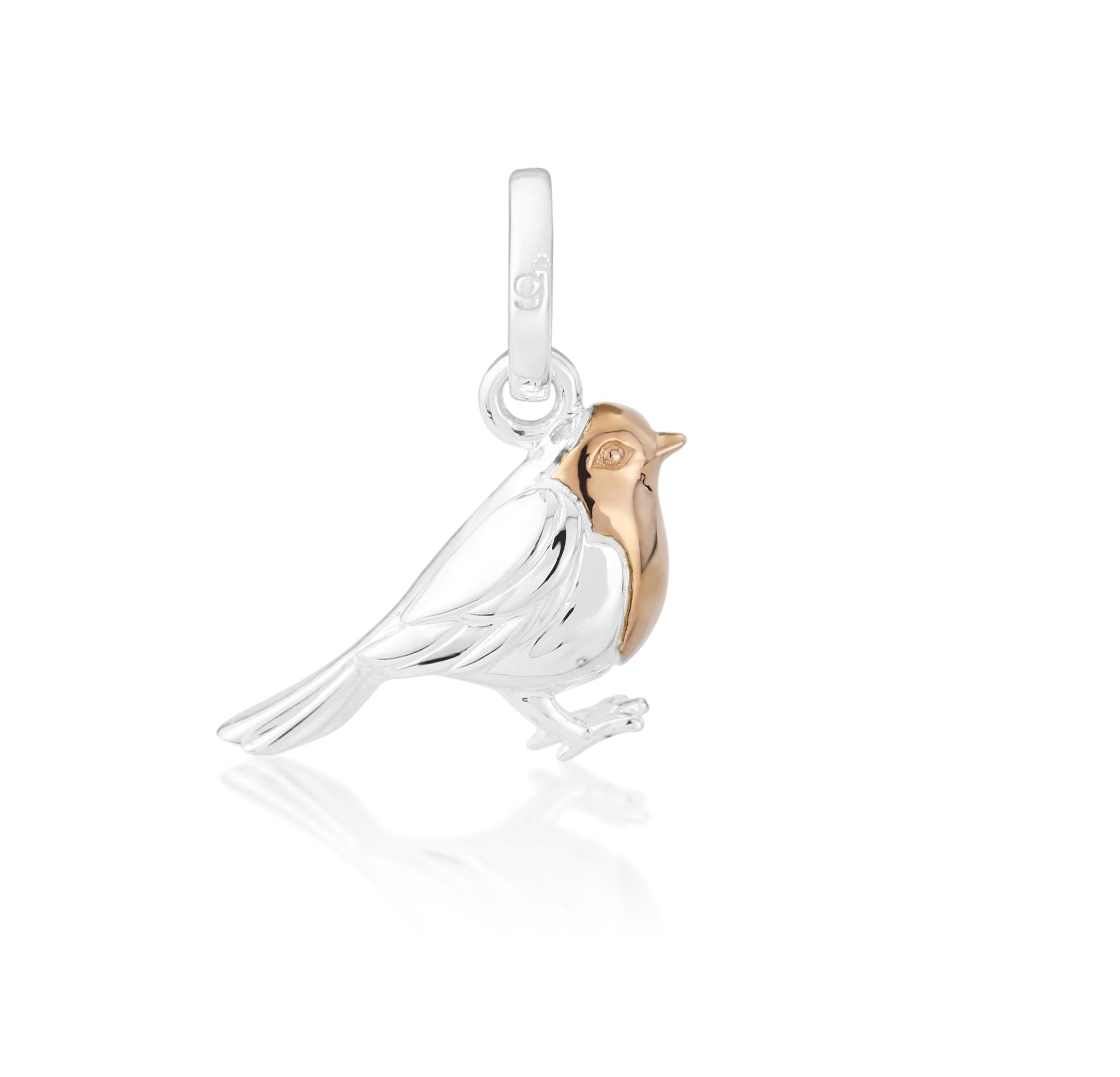 A sterling silver charm shaped like a robin bird with a rose gold breast.