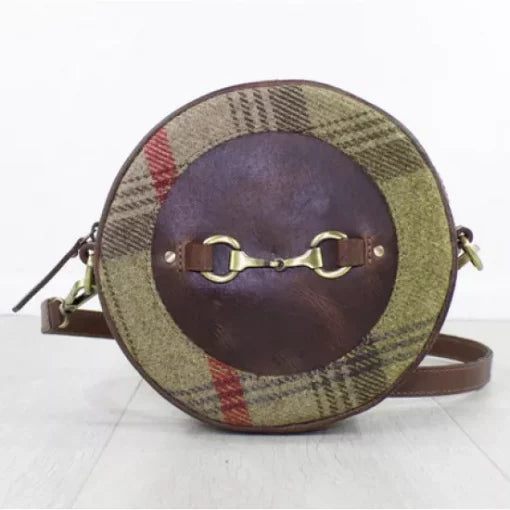 A round brown leather handbag with tweed detailing and a metal bit decoration on the front, featuring a shoulder strap.