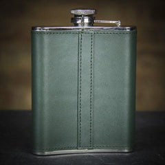 green whiskey flask on a black surface